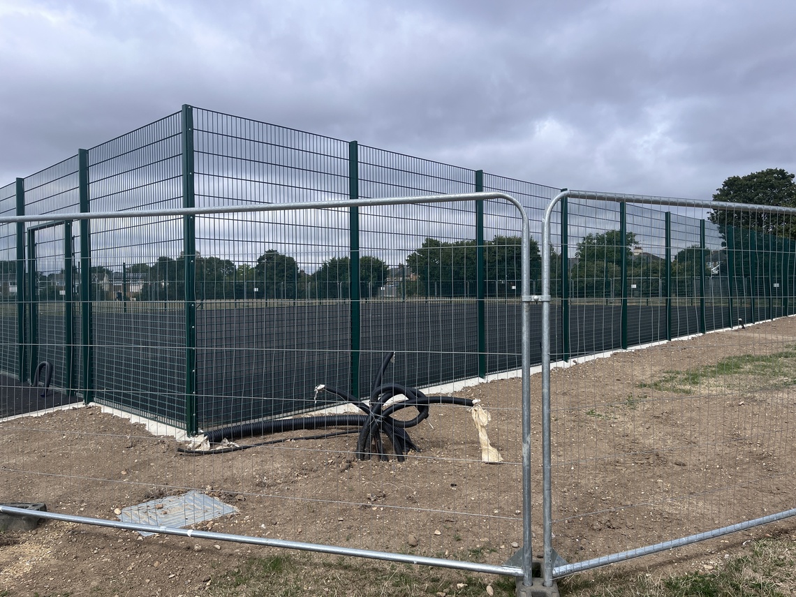tennis court under construction with fencing around it